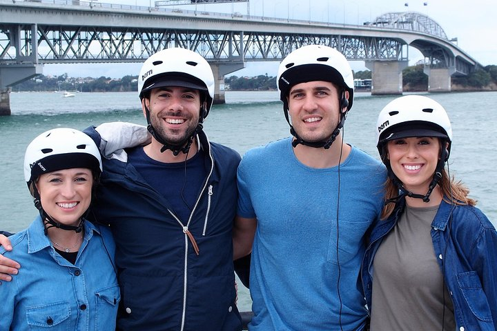 Discover Auckland's highlights on an electric bike riding through scenic neighborhoods with friends creating memorable moments against the backdrop of the iconic bridge.